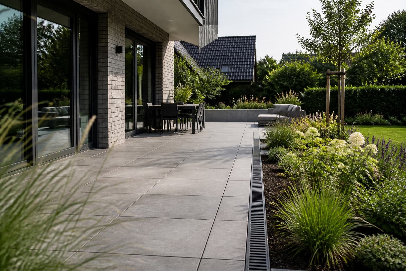 Moderne Terrasse mit großformatigen Keramikplatten und sauberem Übergang zum Garten